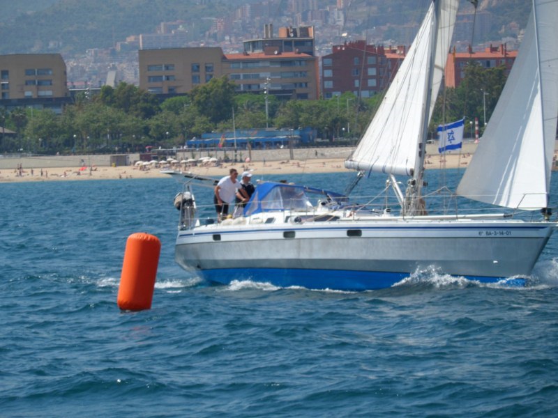 A sailboat passes a buoy in the Barcelona regatta field