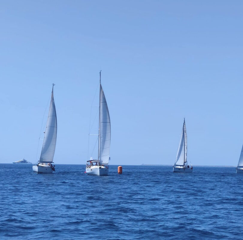 The sailing boats turning the buoy in the regatta field in the coast of Barcelona
